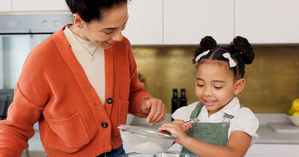 Mother, child and learning for baking with flour helping in the kitchen with recipe or ingredients at home. Happy mom teaching helpful kid to bake or mix together with smile for family bonding time.