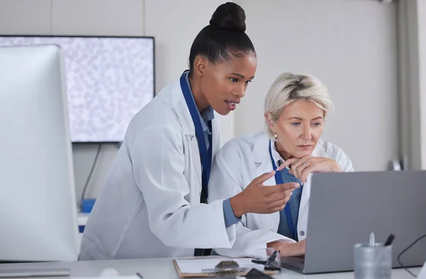 Teamwork, laptop and doctors planning in laboratory for medical research for science. Cooperation, collaboration and researchers, black woman and senior female helping, discussion or brainstorming