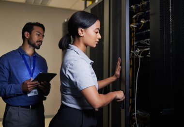 Server room, engineer teamwork and woman opening panel for maintenance or repairs at night. Cybersecurity, programmers and female with man holding tablet for software or networking in data center clipart