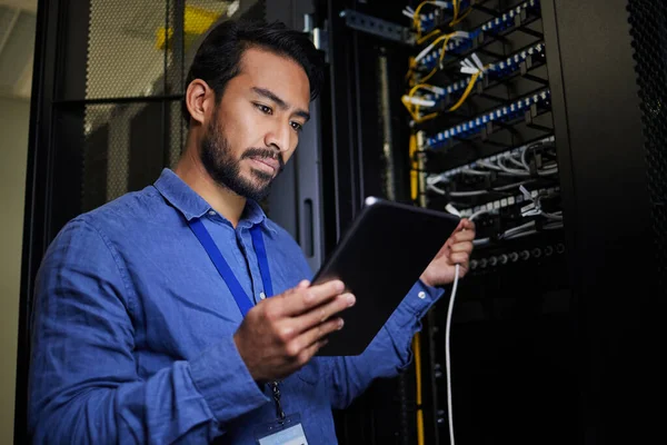 Server room, tablet and engineer with connection cable for maintenance or software update at night. Cybersecurity, it programmer and coder man with technology for database networking in data center