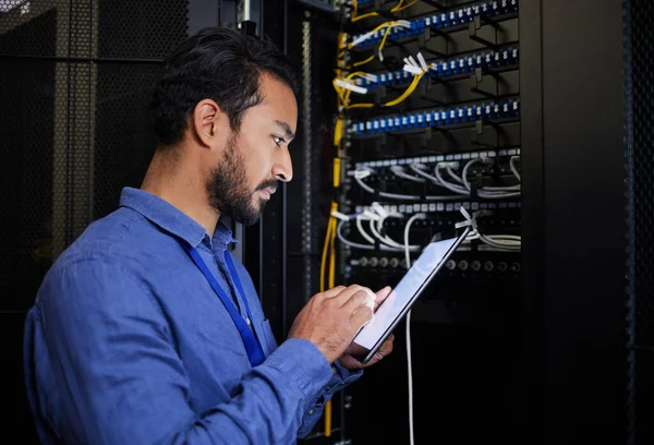Database tablet, server room and engineer man looking at research for maintenance or software update at night. Cybersecurity, it programmer or male coder with technology for networking in data center.