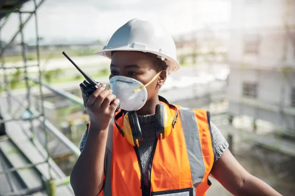 A community on the grow thanks to good old hard work. a young woman using a walkie talkie while working at a construction site
