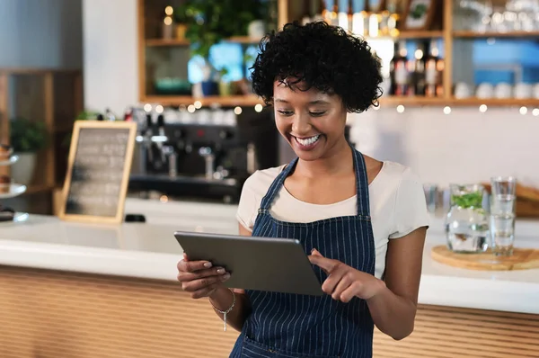 Using digital solutions to best manage her cafe. a young woman using a digital tablet while working in a cafe