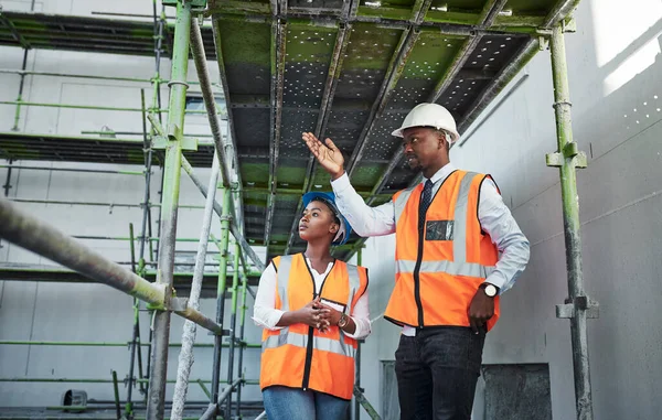 Professional work from the ground to the penthouse. a young man and woman having a discussion while working at a construction site