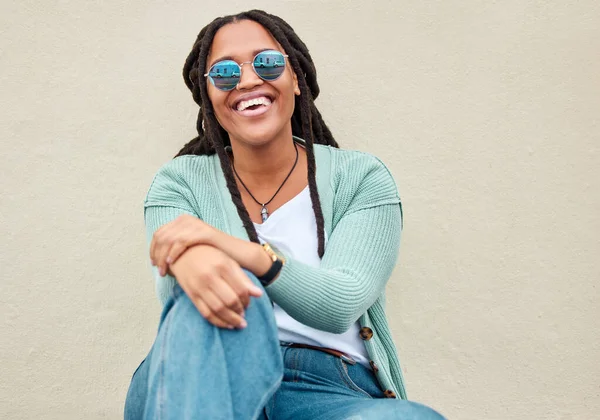 Black woman, sunglasses and city by wall for portrait, happy and smile with fashion in summer. Young gen z, african student girl and outdoor for travel, urban adventure and aesthetic with happiness.