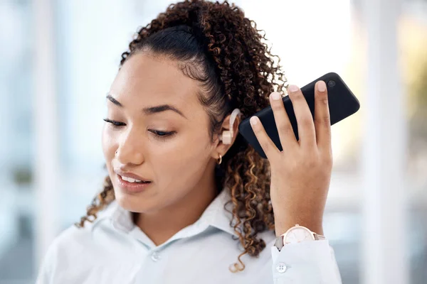 Black woman, phone call and loudspeaker to listen in office with hearing aid for corporate communication. Young executive, smartphone accessibility and disability in workplace with networking.