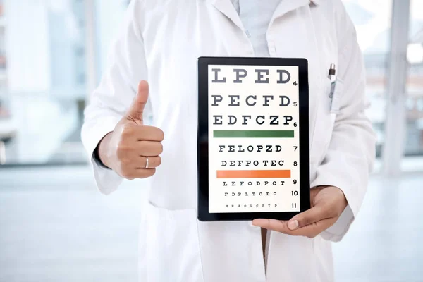 Hands thumbs up, tablet screen and eye chart in hospital for vision examination in clinic. Healthcare, snellen technology or woman, optometrist or doctor with thumbsup emoji and letters for eyes test.