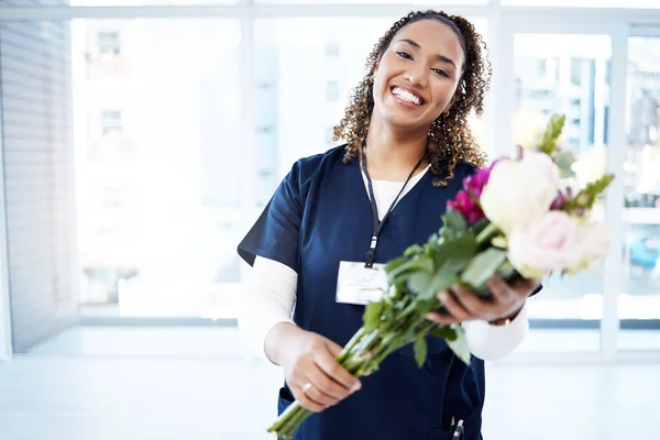 Pride, celebration and portrait of a doctor with flowers at a hospital for promotion and gift for work. Medic, happy and female nurse with bouquet as present for commitment in healthcare nursing job.