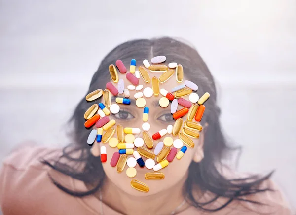 Addiction, pills and medicine on woman face as drug abuse from overhead view looking serious and covered by medication. Tablets, issue and antibiotics problem by mental health patient or female.