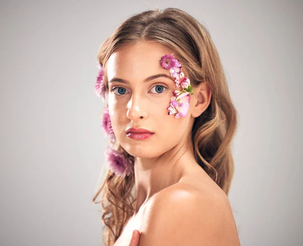 Beauty, flower and portrait of woman in studio for natural cosmetics, skincare wellness and makeup products. Spring, art and girl with petal on face for spa aesthetic, luxury facial and cosmetology.
