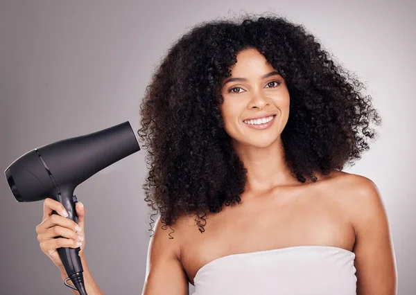 Portrait, beauty and black woman with hair dryer in studio isolated on gray background. Haircare, aesthetic and female model with machine to dry hairstyle after salon treatment for growth or texture