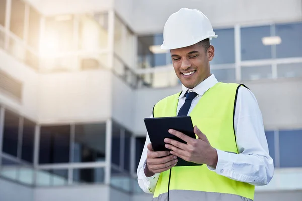 Engineering, digital tablet and man construction worker on outdoor building site in the city. Happy, smile and male industry worker or contractor working on a mobile device for maintenance management.