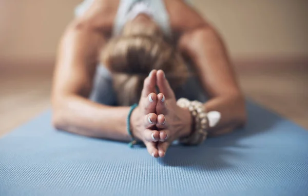 Becoming one with the flow. an unrecognizable woman holding a childs pose during an indoor yoga session alone