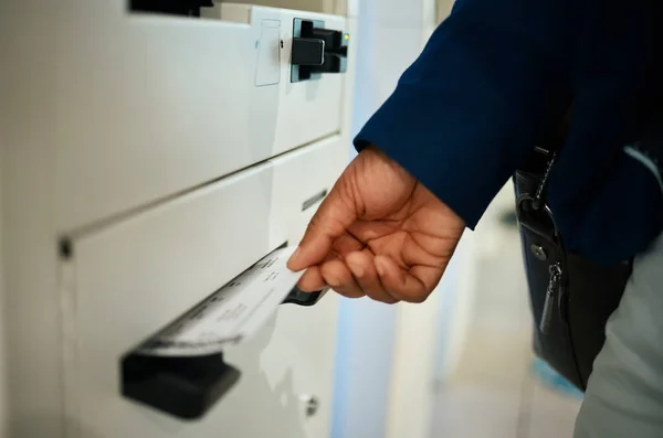 Hands, ticket and airport at self service machine for check in, flight or boarding pass to travel. Hand of traveler taking plane tickets for traveling, trip or journey at airline auto terminal.