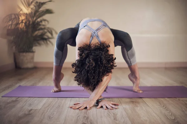 Falling in love with myself through yoga. Full length shot of an unrecognizable woman standing and holding an advanced yoga pose during an indoor session alone