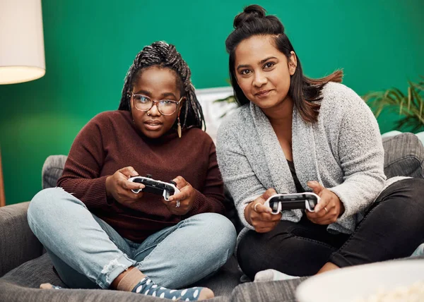 Gaming isnt just for the guys. two young women playing video games on the sofa at home