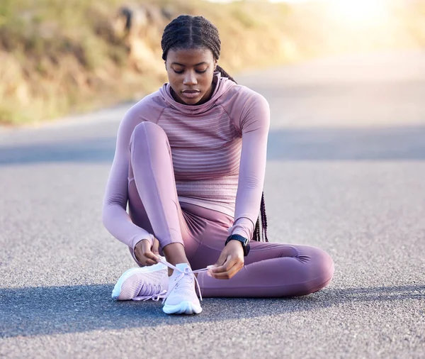 Fitness, road and black woman tie shoes on street to get ready for running, exercise or workout. Sports athlete, training and female runner tying sneakers to start exercising, cardio or jog outdoors