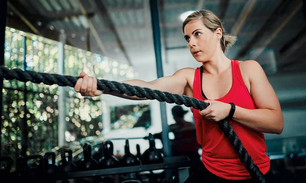 Small battles win the war. an attractive young female athlete working out with battle ropes in the gym