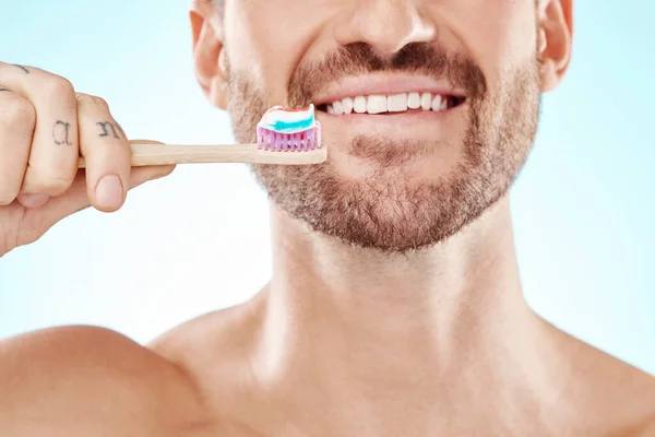 Smile, mouth or happy man brushing teeth with dental toothpaste for healthy oral hygiene grooming in studio. Eco friendly, zoom or male model cleaning with a smile or natural bamboo wood toothbrush.
