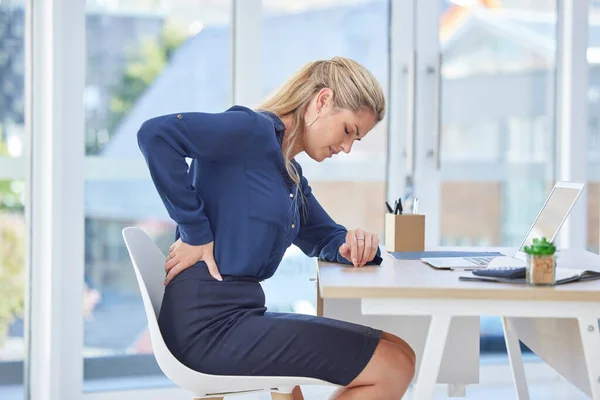 Back pain, office chair and woman with medical, healthcare and muscle problem working at an uncomfortable desk. Burnout, tired and stress of business worker or professional person with spine risk.