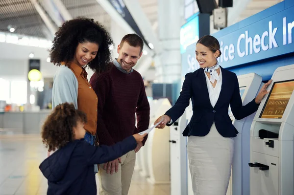 Woman, passenger assistant and family at airport by self service check in station for information, help or FAQ. Happy friendly female agent helping travelers register or book airline flight ticket.