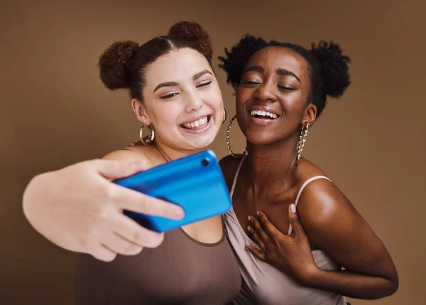Fashion, selfie and friends smile with phone on brown background for wellness, cosmetics and makeup. Beauty influencers, happy and black women on smartphone for social media, picture and online post.
