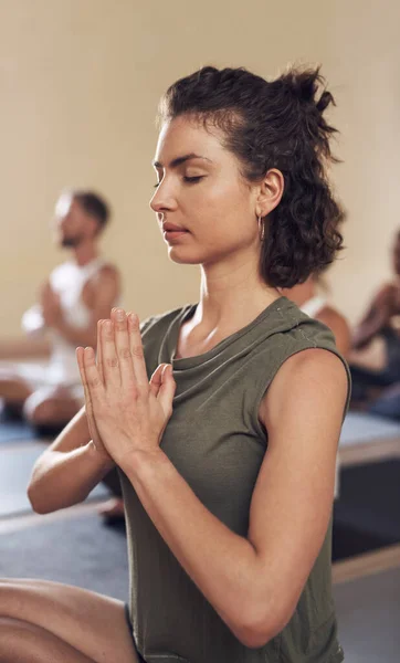 Meditation is good for both your mind and body. an attractive young woman meditating in a yoga class