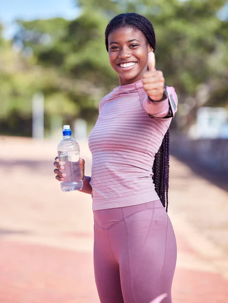Fitness, portrait and black woman thumbs up with water for exercise, health and wellness goals outdoors. Sports training, motivation and happy female athlete with hand gesture for success or support