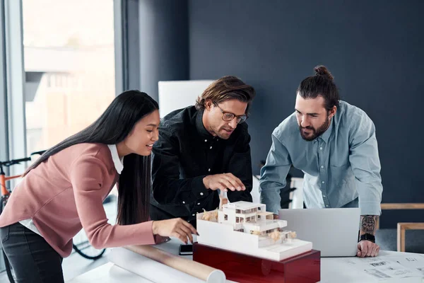 Everyone loves when a good plan comes together. three young architects working on a scale model of a modern house in their office