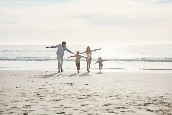 Our family has the right mix of fun and love. Full length shot of a happy young couple enjoying a playful day out with their two children on the beach