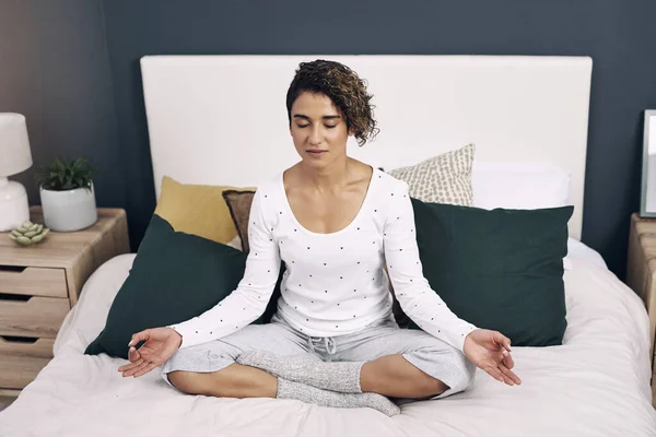 Defeat bad thoughts with good habits. an attractive young woman meditating on her bed at home