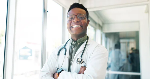 Portrait, healthcare and trust with a black man doctor standing arms crossed in a hospital hallway. Health, medical and insurance with a male medicine professional working in a clinic for treatment.