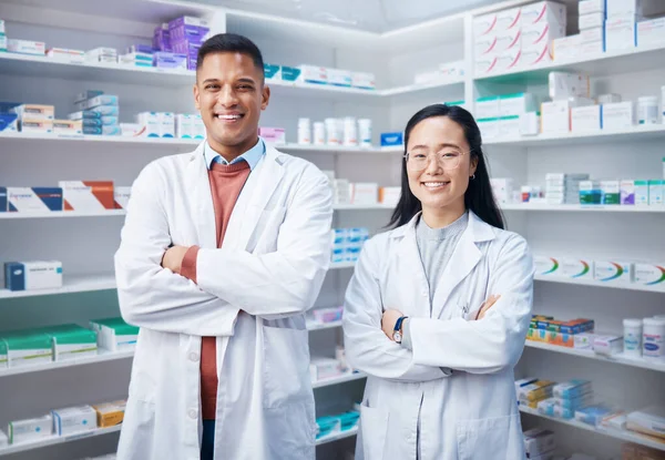 Portrait, teamwork and pharmacists with arms crossed in pharmacy, drugstore and medicine shop. Healthcare, pharma wellness and happy, proud and confident smile of medical doctors, man and Asian woman.