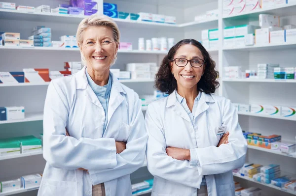 Teamwork, portrait and pharmacists with arms crossed in pharmacy, drugstore and medicine shop. Healthcare, pharma wellness and happy, proud and confident smile of medical doctors or senior women