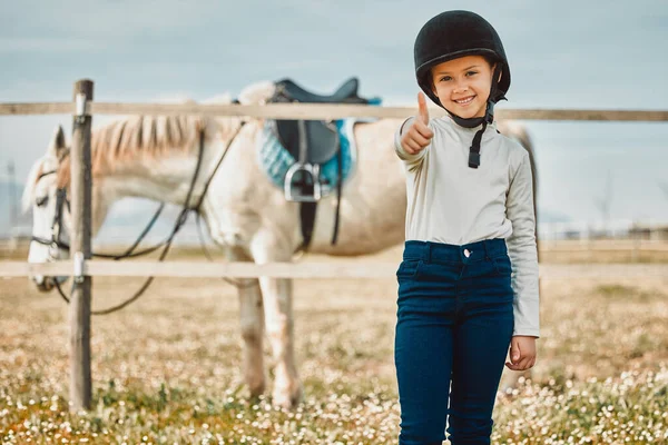 .Happy, thumbs up and horse with portrait of girl in countryside for approval, equestrian and adventure. Winner, goals and smile with child jockey on animal ranch for pet care, pasture and leisure