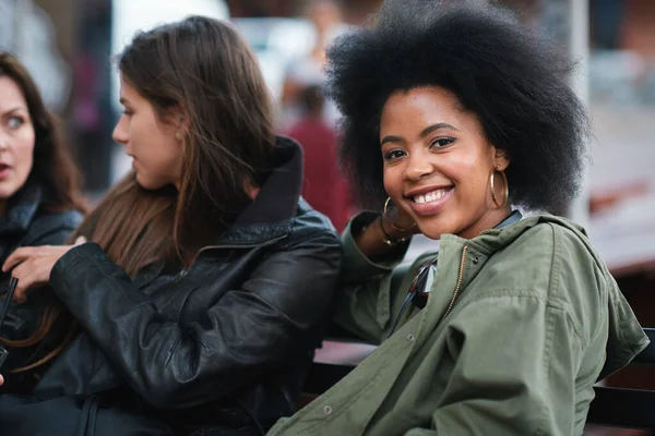 Black woman, portrait and friends outdoor with communication on a urban bench. Happiness, women group and conversation of a young person with a happy smile feeling relax with blurred background.