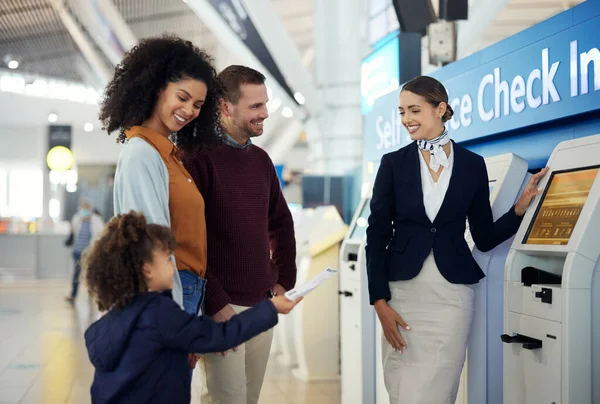 Woman, services agent and family at airport by self service check in station for information, help or FAQ. Happy female passenger assistant helping travelers register or book airline flight ticket.
