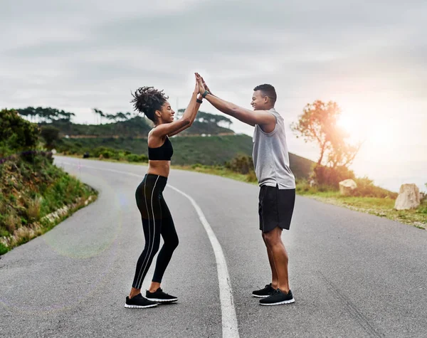 Having that little bit of support really helps. a sporty young couple high fiving each other while exercising outdoors