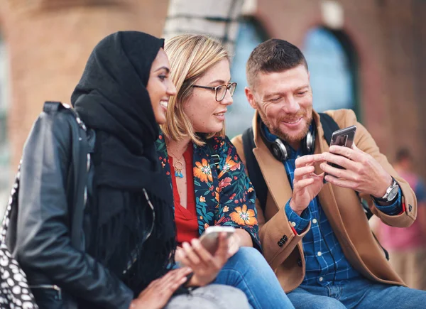 Friends, diversity and happy people with phone communication and funny meme. Hijab, muslim and talking women and adult learning group and international student community on college steps.