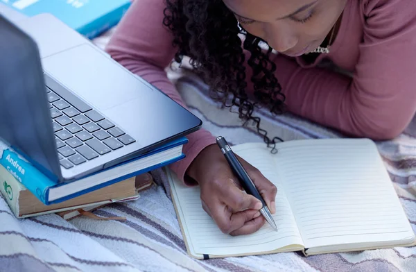 Student, studying and woman writing notes from research assignment for college or university academic education. Park, learning and African American young female Elearning or remote with a textbook.