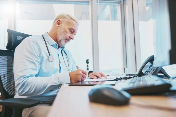 Research, senior man doctor writing in notebook for healthcare, prescription or medicine checklist in office. Focus, thinking or medical worker for hospital schedule, surgery notes or health planning.