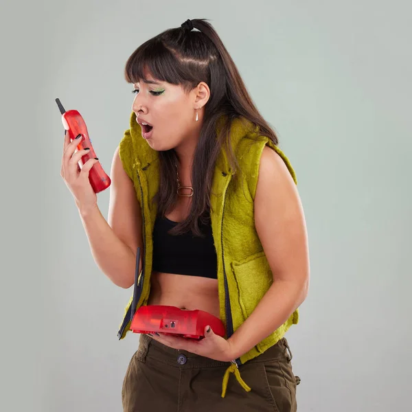 Wow, anger and woman on a telephone call isolated on a grey studio background. Fashion, communication and surprised girl holding a landline phone for conversation, talking and bad news on a backdrop.