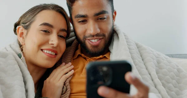 Happy, couple with phone for communication, networking or social media app at home. Movie, video or love man and woman relax in living room streaming online, internet or website with smile in house.
