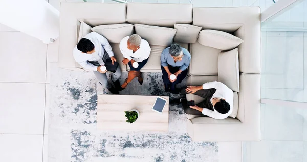 Corporate, lounge and business people on couch, relax and talk during lunch break with company chill spot top view. Diversity, social and employee group together with tablet and coffee break.