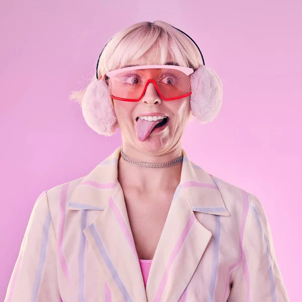 Fashion, comic face and a woman quirky in studio with tongue out on a pink background. Aesthetic model person with funny glasses for edgy vaporwave trend with creativity, comedy and color for art.