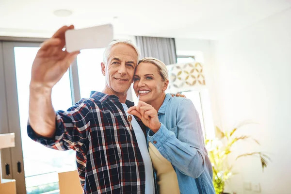 Look who bought their dream home. a happy mature couple taking a selfie on moving day
