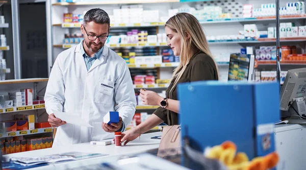 He puts her health first. a mature pharmacist assisting a young woman in a chemist