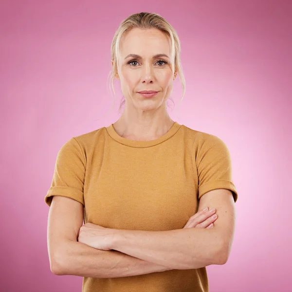 Portrait, serious and woman with arms crossed on pink background, studio and backdrop color in Canada. Mature female model, focus and confidence of women empowerment, leadership and mindset of vision.