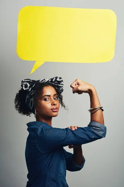 She has a message of power to spread. Studio shot of an attractive young woman posing with a speech bubble against a grey background
