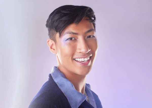 Makeup, smile and portrait of gay man from Indonesia with confidence isolated on purple background. Happy, aesthetic and lgbt fashion model with beauty in studio, non binary and gender neutral design.
